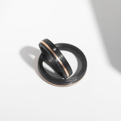 Leicht abgerundete Eheringe aus Carbon und Gold mit Diamant Lise