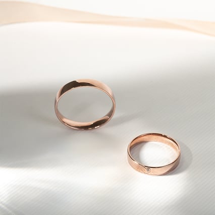 Goldene Eheringe mit einem Herzen und einem Diamanten Maline