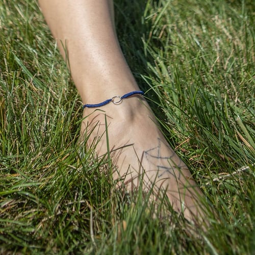 String-Armband mit einem Anhänger in Form des Karma-Symbols Karma