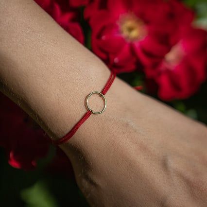 String-Armband mit einem Anhänger in Form des Karma-Symbols Karma