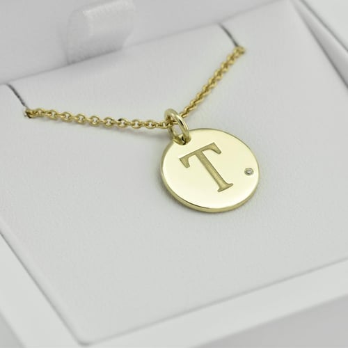 Goldener Anhänger mit Diamant und Gravur eines Buchstabens Sager