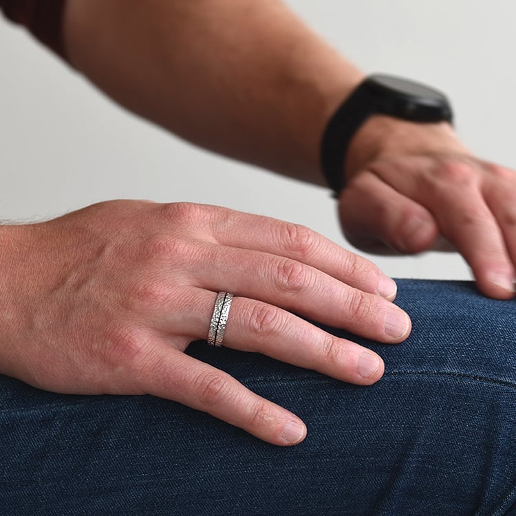 Unkonventioneller gehämmerter Trauring mit schwarzer Füllung auf dem Finger 64151