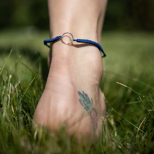 String-Armband mit einem Anhänger in Form des Karma-Symbols Karma