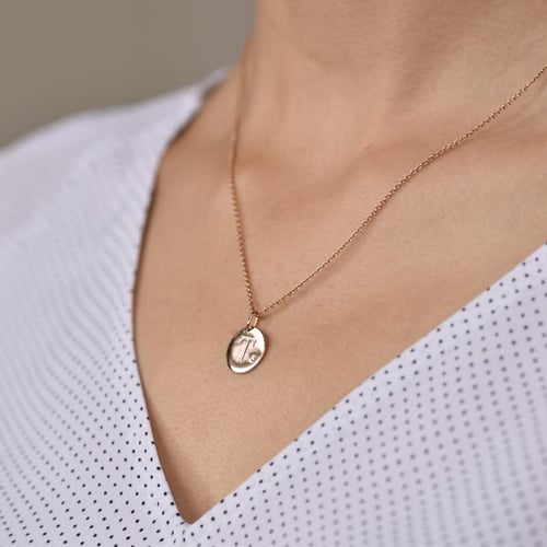 Goldener Anhänger mit Diamant und Gravur eines Buchstabens Sager
