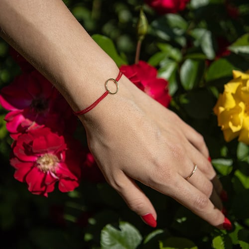 String-Armband mit einem Anhänger in Form des Karma-Symbols Karma